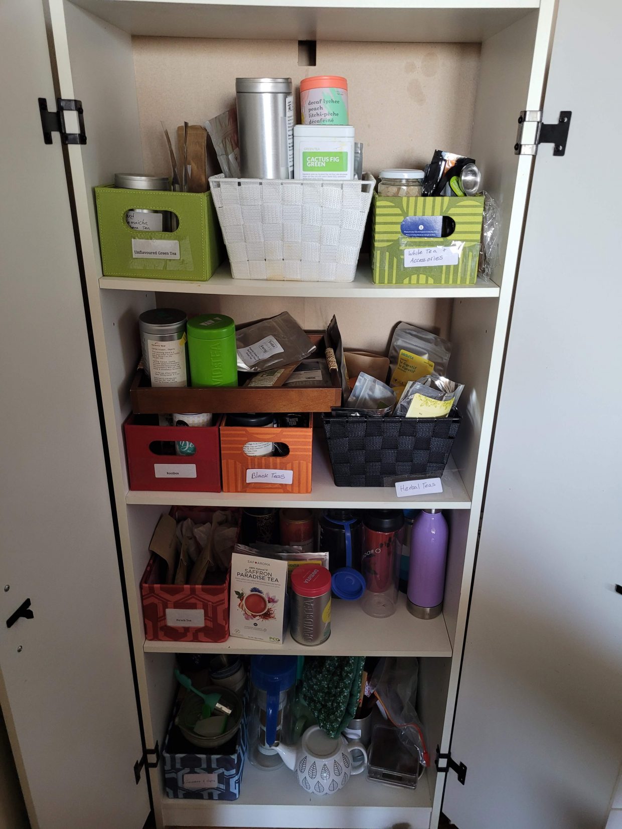 A photo of my white tea cabinet, with shelves full of different teas in smaller containers