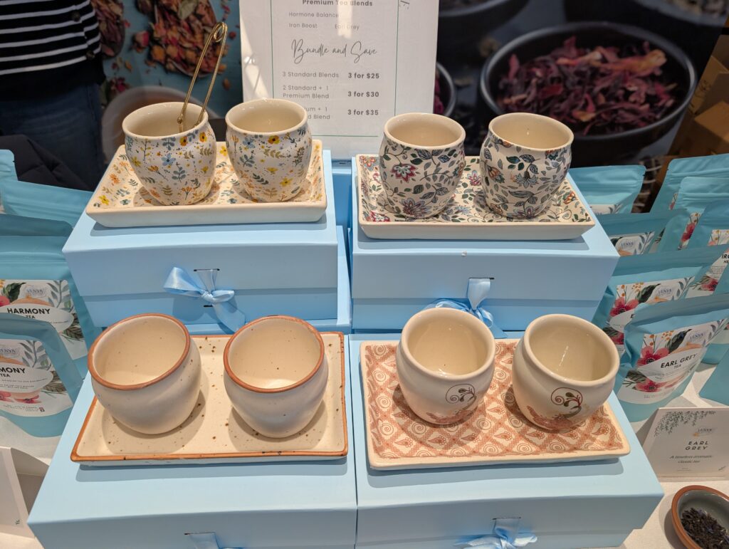 Four different sets of brightly-patterned ceramic cups. Each set contains two cups sitting on a matching plate.